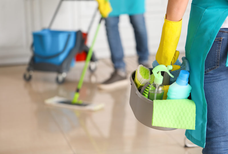 Två personer som städar med rengöringsprodukter och moppar golvet. Städ Lund